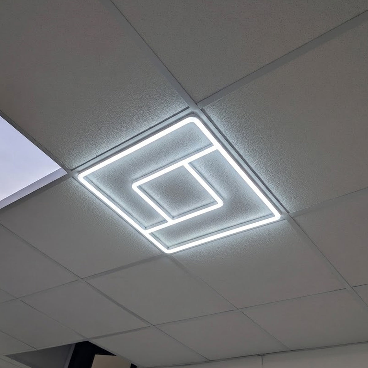 Greek Key linear frame light installed and lit in a real ceiling grid