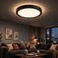 Black round LED panel light installed on a modern living room ceiling